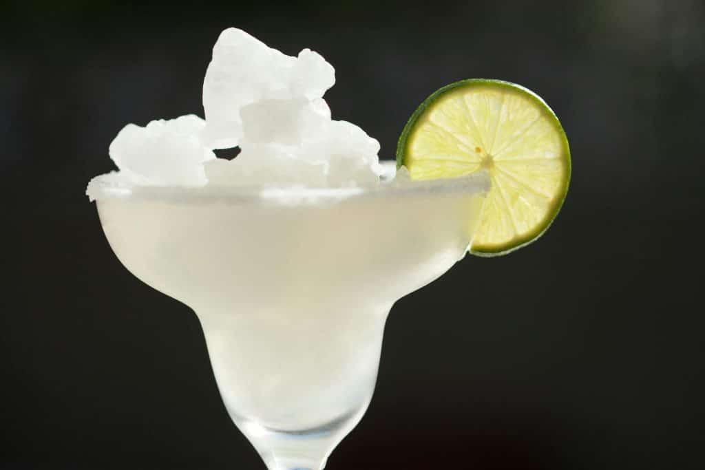 Close-up of a classic frozen margarita in a glass with lime garnish, perfect for summer refreshment.